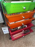 Multicoloured plastic drawer unit with five drawers containing beads