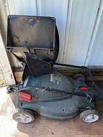 Side view of the green Craftsman electric mower showing grass collector and wheels, exhibiting use and dirt.