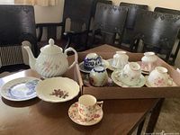 Wide shot showing assortment of porcelain cups, saucers, and teapot on table