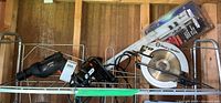 Full view of all four tools in wire rack: Black and Decker circular saw, Mastercraft grip, Bostik glue tool, Craftsman drill.
