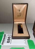 Vintage Dunhill lighter in its original brown box with soft peach satin interior and gold Dunhill crest and logo.