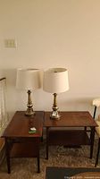 Photo of two vintage wooden end tables side by side with lamps on top, showing front and top surfaces.