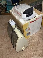 Electric heater shown from side and front, cord wrapped around unit, beige with metal grille