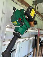 Photo showing the full side view of the green FeatherLite Weed Eater trimmer, revealing motor and handle area with some rust and wear.