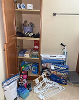 Wide photo showing wooden cabinet with various health and personal care items including Dr. Ho's Circulation Promoter box, Snuggie blankets, a grabber tool, hangers, and other boxed items