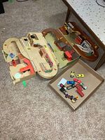 Two folding play centres on carpet with 12 toy cars in open box