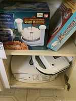 Hamilton Beach griller under cabinet with boxed Onion Machine and Micro Hot hot plate on shelf above