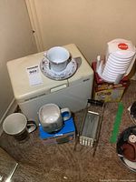 Wide view showing the Welbilt bread maker, teacup and saucer on top, large mugs, egg extractor box, and French fry cutter