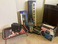 Overview of the lot showing Kodak Brownie camera on E.T. dinner tray, Casio keyboard, gumball machine, telescope, cassette recorder, constellation finder box.