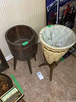Two plant stands side by side on carpet, one wooden barrel and one ceramic pot on wooden legs