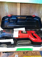 Reciprocating saw in black plastic carrying case showing tool body and handle.