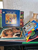 Photo showing multiple read-along books and vinyl records, prominently featuring Lionel Bart's Oliver!, Olivia Newton-John's Grease, and other albums.