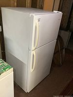 Full side view of the white Frigidaire refrigerator with freezer on top, showing overall shape and condition.
