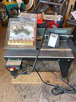 Full view of Craftsman router table with attached router, power cord, and set of router bits on top.
