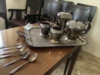 Full overview of the entire set on dining table showing coffee pot, tea pot, cream and sugar containers with mixed spoons on large serving tray.