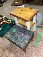 Photo showing both the small wooden table and the vintage foot stool together on carpeted floor with packaging and other items in background.