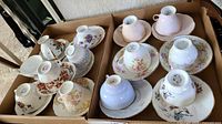 Box with 12 floral fine china teacups and their matching saucers in various pastel shades and patterns