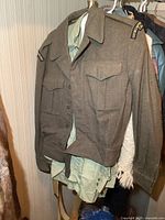 Front view of vintage wool military uniform jacket over light green shirt, showing button closures and flap pockets.