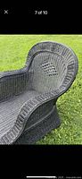 Close-up of black wicker chaise lounge showing diamond weave detail on side arm and curved design.