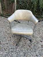 Front view of the vintage office chair showing off-white vinyl with marbled finish, low backrest, and chrome arms.