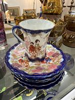 Vintage Japanese tea set with one flared cup and four dessert plates featuring geisha figures, floral patterns, cobalt blue and gold accents