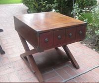 Front left perspective of the square wood side table with visible drawer fronts and X-base legs.