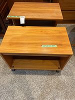 Two small wood finish tables, one rolling printer cart with wheels and one small table with shelf. Dimensions visible on tape.
