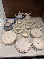 Full set displayed on table showing teacups, saucers, plates, creamer, and teapot.
