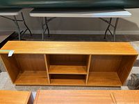 Front view of wooden bookcase on carpet showing three open compartments