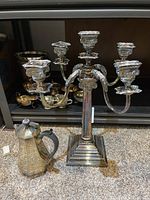 Silver-plated five-arm candelabra with decorative arms and stepped square base for candle holders