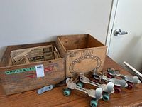Two vintage wooden crates and two pairs of vintage roller skates placed side by side on the floor against wall.
