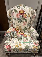 Front view of the floral wingback chair with matching round cushion resting on the seat.