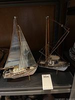 Two glass and metal model sailboats displayed on a shelf holding lot tag 804.