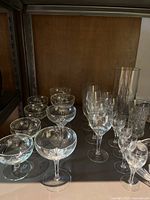 Various clear stemmed glass dessert and cocktail glasses arranged on a shelf.