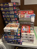 Stack of puzzle boxes showing various brands, piece counts, and artwork mainly by Jan van Haasteren and others