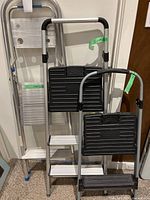 Three step ladders of various sizes grouped together, showing overall size and structure.