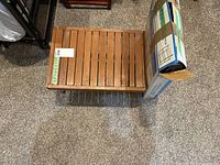 Top view of the small wooden outdoor table with a slatted top and part of the cardboard box placed on it.