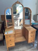 Front view of solid wood vanity with three mirrors (center arched, two side) and drawers on each side.