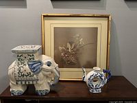 Photo showing all three items: framed Chinese floral artwork, ceramic elephant, and blue and white teapot