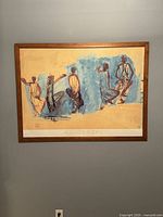 Large framed print on wall showing five stylized dancer sketches against beige and blue wash background with wooden frame