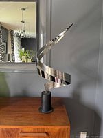 Front view of the stainless steel ribbon swirl sculpture on black base