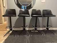 Front view of four barstools in a row against wall