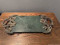Top view of green marble serving tray showing the rectangular base and silver-plated grape and vine handles at both ends.