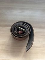 Rolled brown leather belt showing edges and buckle