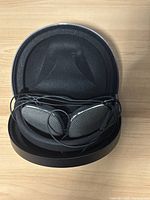 Bowers & Wilkins wired headphones placed inside the open black molded hard case on a wooden surface.