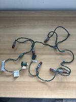 String of Budweiser hockey themed light bulbs on green wiring with visible plug and some missing bulbs.