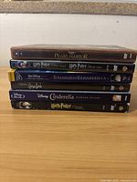 Six DVD cases stacked horizontally on a wooden surface showing spine titles.