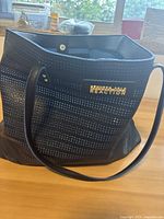 Front view of the blue Kenneth Cole Reaction bag showing perforated leather and gold logo