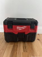 Closed view of the Milwaukee branded red and black plastic carrying case for M18 vacuum.