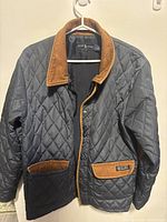 Front view of the navy blue quilted jacket showing brown corduroy collar, pocket trims, and snap button closures.